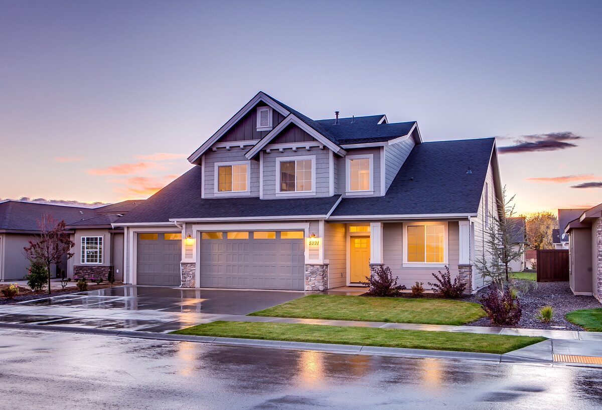 Modern multi-gabled two-story suburban home with grey siding, stone accents, and an attached garage at sunset, representing residential properties inspected by Northmark Property Inspections in Appleton, WI.