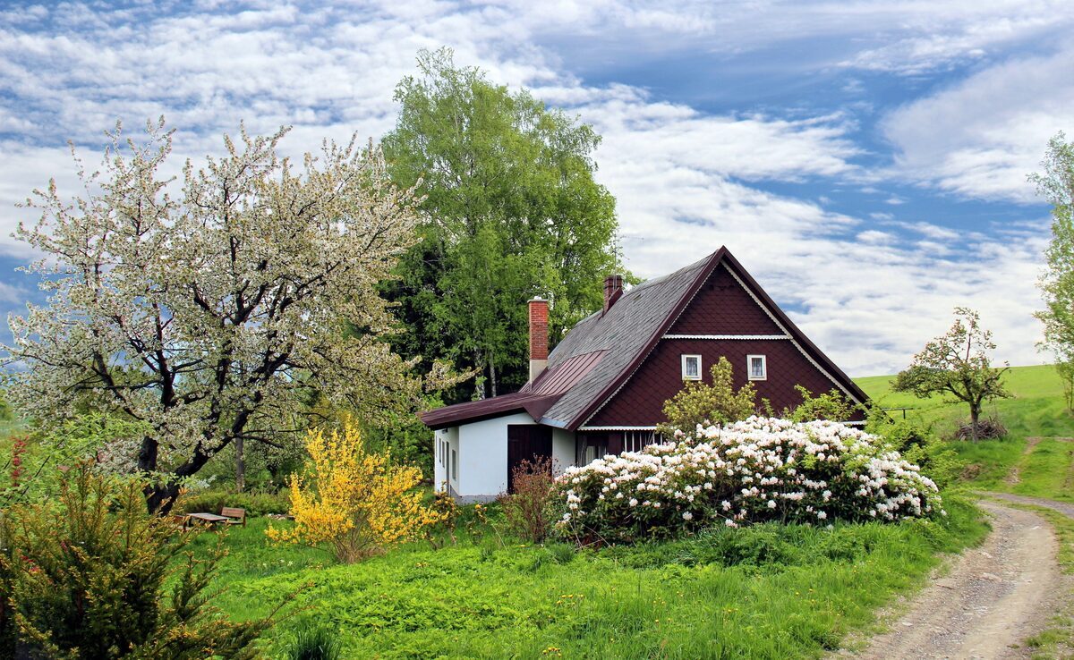 Charming countryside cottage-style home surrounded by lush green lawns and blooming spring trees, representing residential properties inspected by Northmark Property Inspections in Crivitz, WI.
