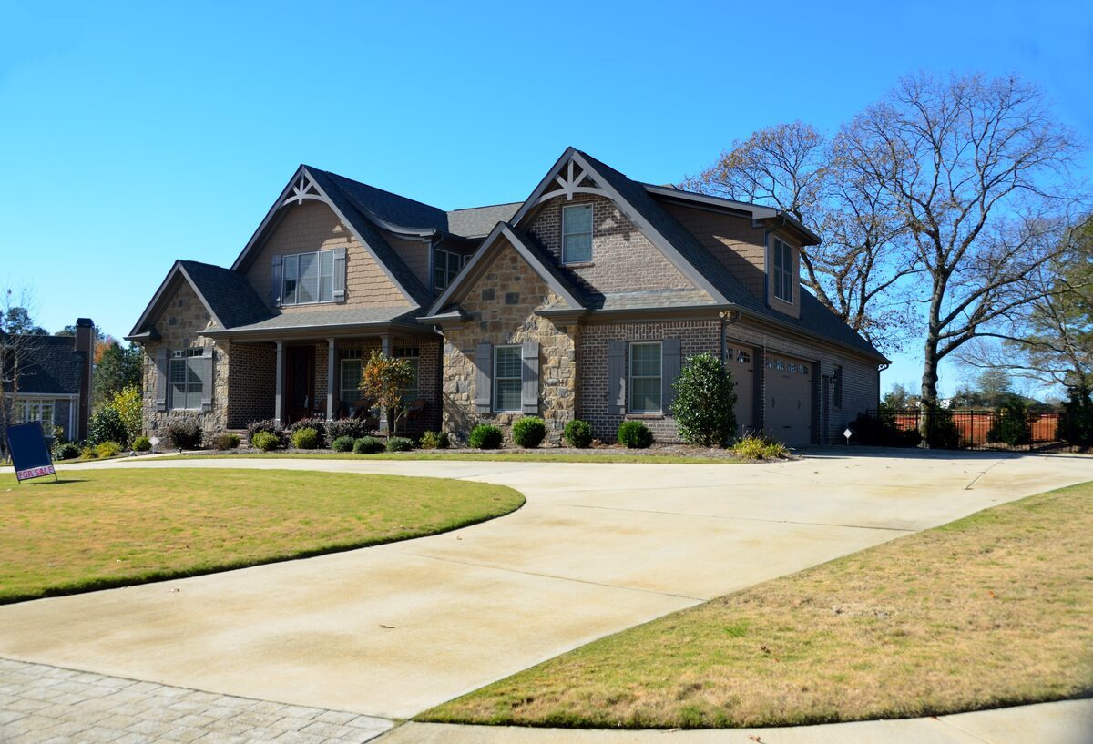 Stately multi-gabled home with a stone and brick facade, shake siding accents, and a curved concrete driveway, representing residential properties inspected by Northmark Property Inspections in Denmark, WI.