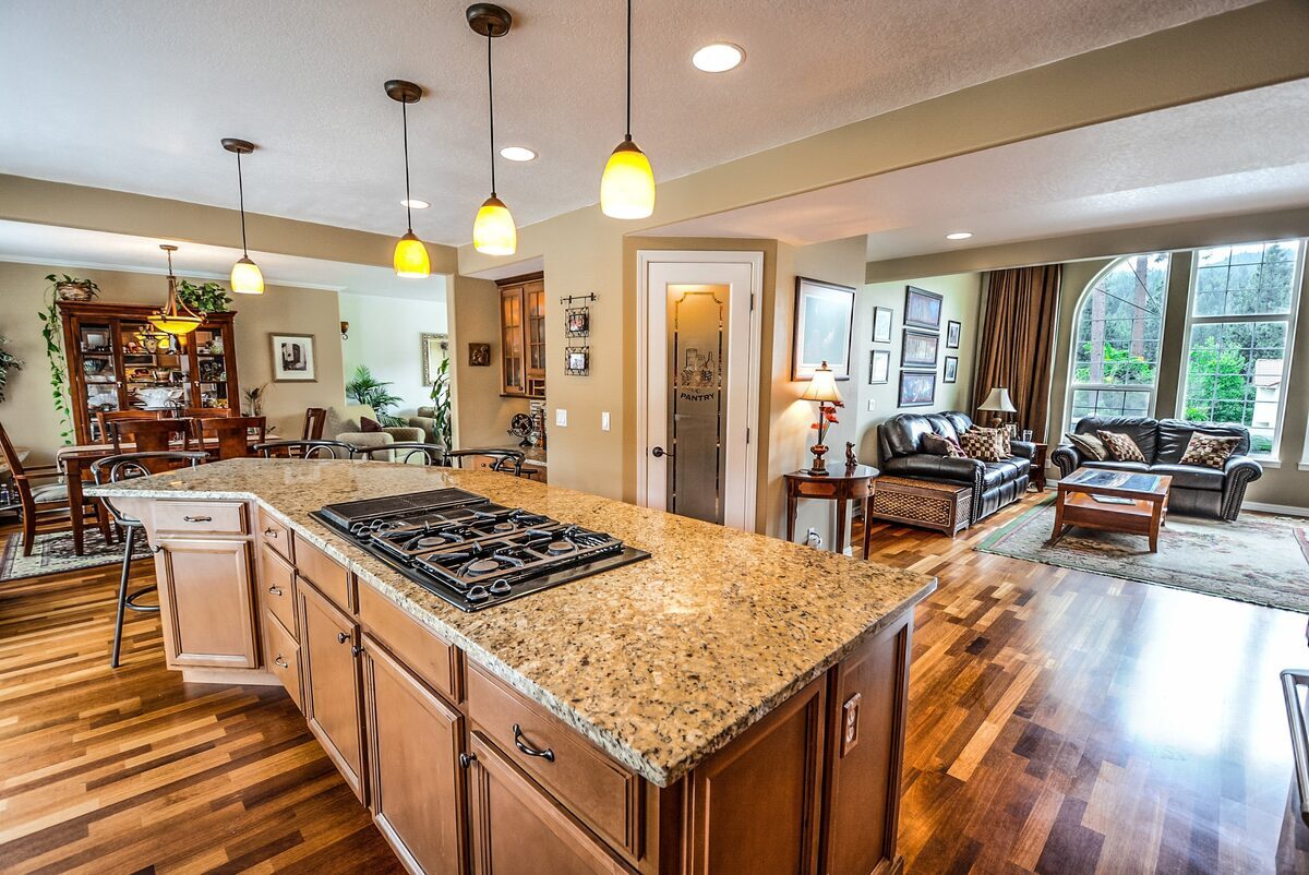 Spacious open-concept home interior featuring a large kitchen island with granite countertops, hardwood floors, and an adjacent living room, representing residential properties inspected by Northmark Property Inspections in Marinette, WI.