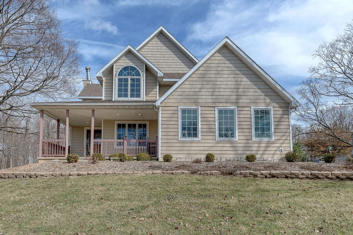Multi-gabled suburban home featuring tan shake and horizontal siding with a spacious front porch, representing residential properties inspected by Northmark Property Inspections in Suring, WI.